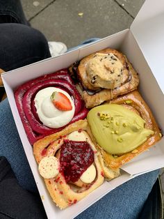 a box filled with assorted pastries on top of a person's lap