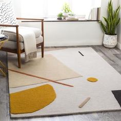 a living room area with a chair, rug and potted plant