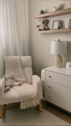 a white chair with a teddy bear sitting on top of it next to a dresser