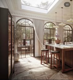 a kitchen with an island and two stools in front of the counter top, surrounded by arched windows