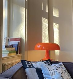 an orange lamp sitting on top of a table next to a window