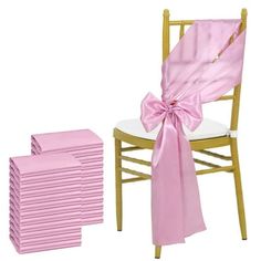 a stack of pink chair sashes next to a stack of white chairs