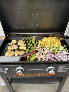 an outdoor grill with various vegetables and meats cooking on the griddle for bbq stone