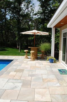 a patio with an umbrella and pool in the background