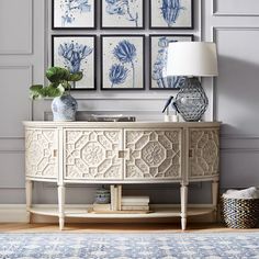 a white and blue vase sitting on top of a wooden table next to a lamp