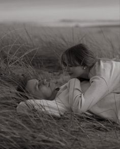 a woman laying in the sand with her head on another woman's shoulder and looking at each other