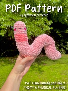 a pink crocheted worm is held up to the camera