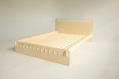 a wooden bed frame sitting on top of a white floor next to a wall in the background