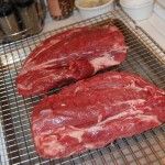 two raw steaks sit on a wire rack