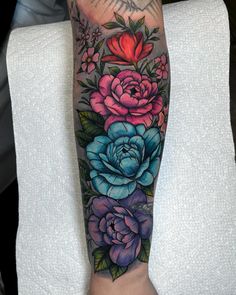 a woman's arm with flowers and leaves on the side of her body, which is covered in tattoos