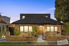 a brick house with an iron fence in the front yard