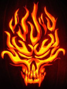 a carved pumpkin with flames in the shape of a demon's head on it