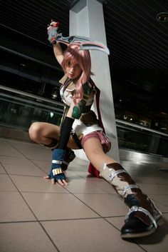 a woman dressed in cosplay clothing kneeling on the ground with her arm up