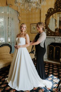 a woman in a wedding dress is helping another woman get ready to walk down the aisle