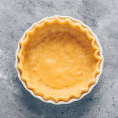 an uncooked pie crust in a white bowl on a gray surface with a spoon