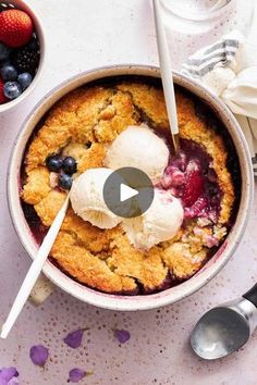 a bowl filled with fruit and ice cream on top of a white table next to two bowls