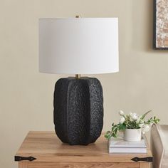 a table lamp sitting on top of a wooden dresser next to a white flower pot