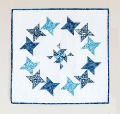 a blue and white quilted wall hanging with many stars on the front, one in the middle