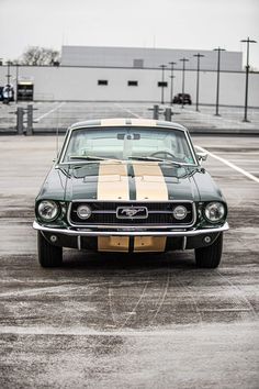 an old muscle car parked in a parking lot with its hood down and stripes painted on the front