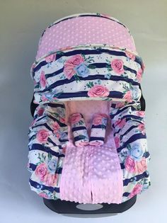 an infant car seat with pink flowers and blue stripes