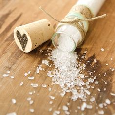 a bottle filled with sea salt sitting on top of a wooden table next to a cork