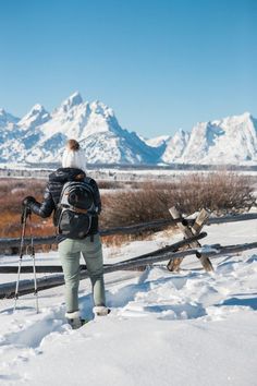 a person standing in the snow with skis on their back and poles attached to them