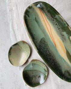 three green dishes sitting on top of a white cloth