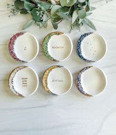 six porcelain dishes with names on them and flowers in the background