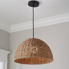 a wicker light fixture hanging from the ceiling in a living room with white walls