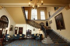 an ornate staircase with blue chairs and chandelier