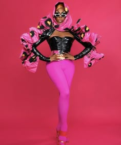 a woman in pink and black is posing with her hands on her hips while wearing a mask