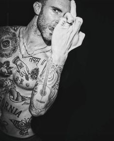 a man with tattoos holding his hand up to his face