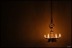 a chandelier with five candles lit in the dark