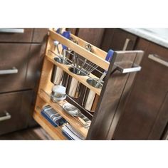 an open drawer in a kitchen with dishes and utensils on the bottom shelf