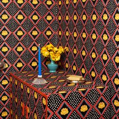 a vase with yellow flowers sitting on top of a table next to a black and white wall