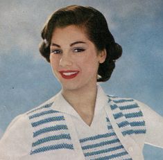 an old photo of a woman wearing a white sweater and blue striped vest, smiling at the camera