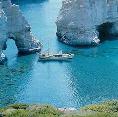 a boat is in the water between two large rocks