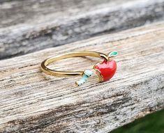 This adorable ring has a red apple on one side and a little worm on the other. The ring is adjustable. This would make a great gift for a birthday, an anniversary, Christmas or any other occasion. Smallest adjustable ring size is probably a 6.5, adjustable up to size 10, so meant for ages 10+. Too large for little kids. Metal: alloy, enamel All jewelry items come in a gift box. Whimsical Sterling Silver Ring For Gift, Adjustable Fun Rings For Gifts, Cute Red Ring As Gift, Red Novelty Jewelry For Birthday, Cute Red Ring For Gift, Personalized Red Rings As Gift, Personalized Red Rings For Gifts, Valentine's Day Gift Adjustable Birthstone Ring, Personalized Red Rings For Gift