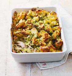 a casserole dish with chicken, broccoli and potatoes on a napkin