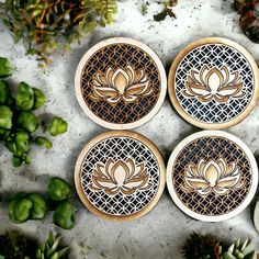 four decorative wooden coasters sitting on top of a table next to succulent plants