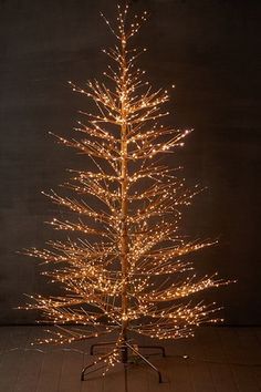 a lighted christmas tree on a stand in front of a dark background with no lights