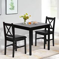 a small table with two chairs and a vase filled with flowers on top of it