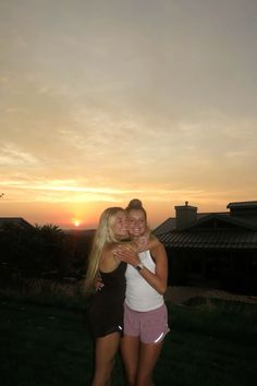 two women hugging each other in front of a sunset