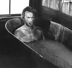 a man sitting in an old bathtub with his face partially covered by the water