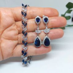 "Blue bridal jewelry set, sapphire wedding jewelry for brides, sapphire drop earrings, bridal jewelry set, sapphire jewelry, bridal jewellery, navy blue prom jewelry, blue bridal earrings Beautiful and very sparkly bridal earrings with blue sapphire Cubic Zirconia teardrops in Luster rhodium plated settings and rhodium plated Cubic zirconia connectors. The earrings dangle from high quality  CZ set ear posts . (High quality plating, Anti tarnish, hypoallergenic). *The earrings length is 45mm. * Matching bracelet: made with clear and sapphire marquise cut Cubic Zirconia set in high quality rhodium plating. The bracelet measures 7inches long and closes with fold over clasp. It fits best 6-6.5\" wrists. (Please, measure snug around your wrist before ordering and contact me, if your wrist is bi Blue Prom Jewelry, Blue And Silver Jewelry, Blue Bridal Jewelry, Navy Blue Jewelry, Blue Bridal Earrings, Jewelry For Brides, Navy Blue Earrings, Jewelry Sapphire, Quince Decorations