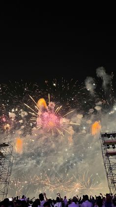 fireworks are lit up in the night sky above a stage with people standing on it