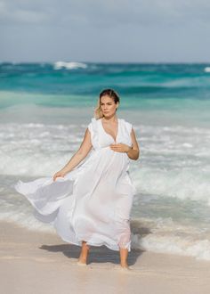 a woman in a white dress is walking on the beach