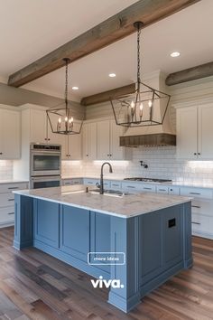 a large kitchen with an island in the middle of it and two pendant lights hanging from the ceiling