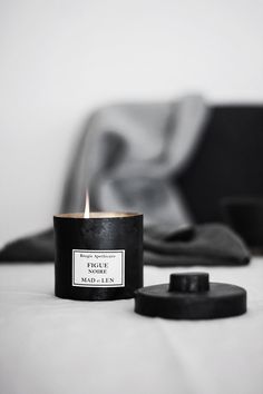 a candle sitting on top of a bed next to a black bag and pillow in the background