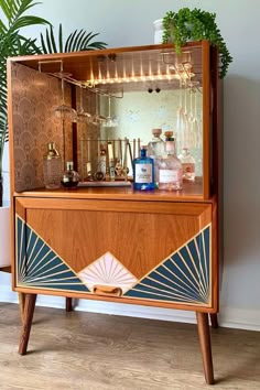 a wooden cabinet with an art deco design on the front and sides, along with a potted plant